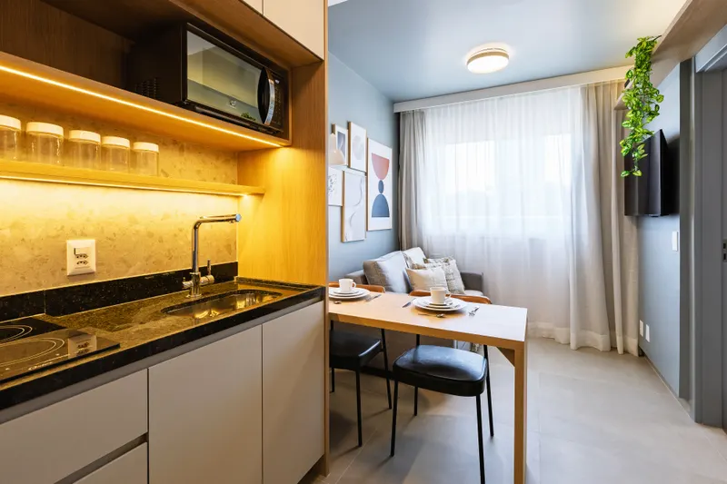 Cozinha compacta de studio com marcenaria planejada e iluminação embutida