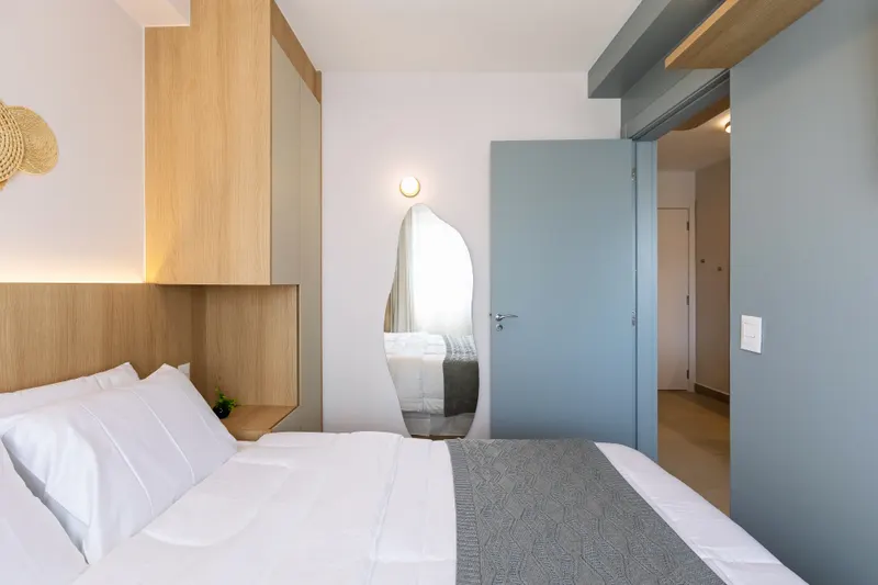 Área de dormir de studio com cabeceira em madeira e marcenaria sob medida